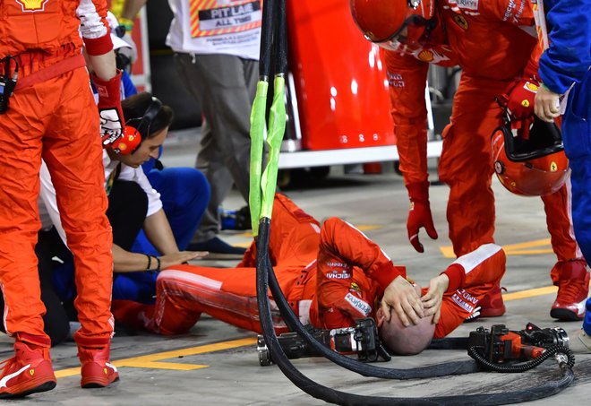 Ferrarijev mehanik Francesco Cigarini se je zvijal od bolečin, potem ko ga je z dirkalnikom nesrečno zadel Kimi Räikkönen. FOTO: AFP