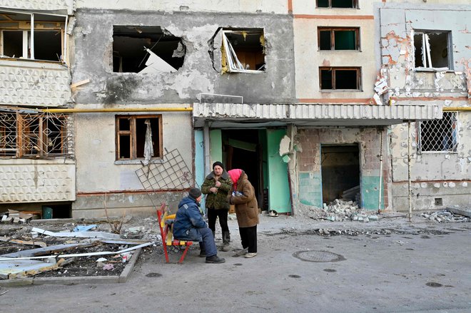 Starejša prebivalca pred uničeno stanovanjsko zgradbo v Harkovu. FOTO: Sergey Bobok/AFP
