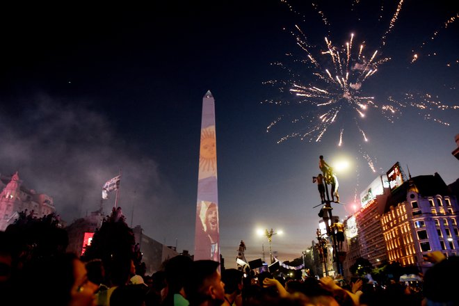 Argentinski navijači praznujejo pri obelisku s podobo Messija in ognjemetom. FOTO: Mariana Nedelcu, Reuters
