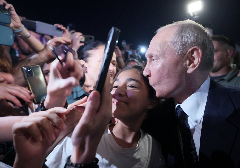 Fotografija: Ruski predsednik Vladimir Putin je mlado damo poljubil na čelo. FOTO: Gavriil Grigorov, Sputnik Via Reuters