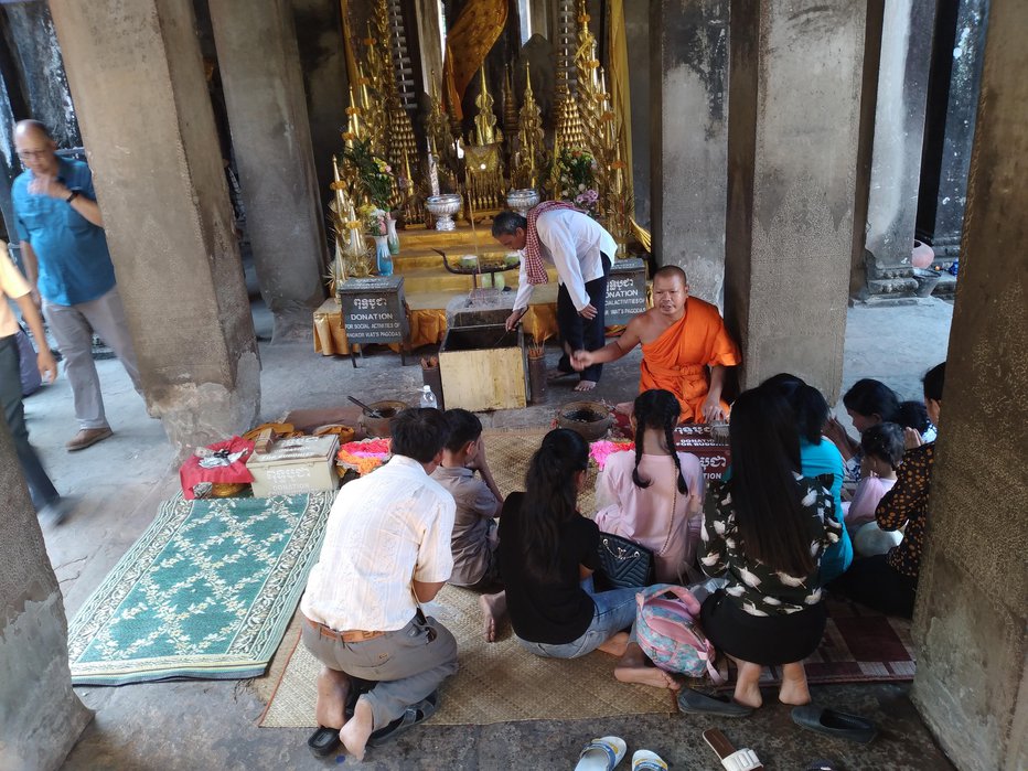 Fotografija: Menih v Angkor Watu opravi obred z družino turistov. FOTO: Tomica Šuljić
