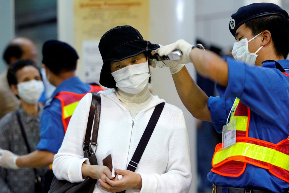 Fotografija: Zdravstveni delavci na železniških postajah in letališčih potnikim merijo vročino. FOTOGRAFIJE: REUTERS