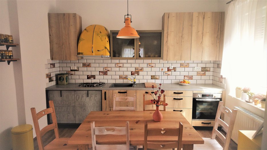 Fotografija: Kuhinjo v naravnih odtenkih z rumenimi poudarki zaznamuje provansalski slog opreme. FOTO: Blaž Vehovar