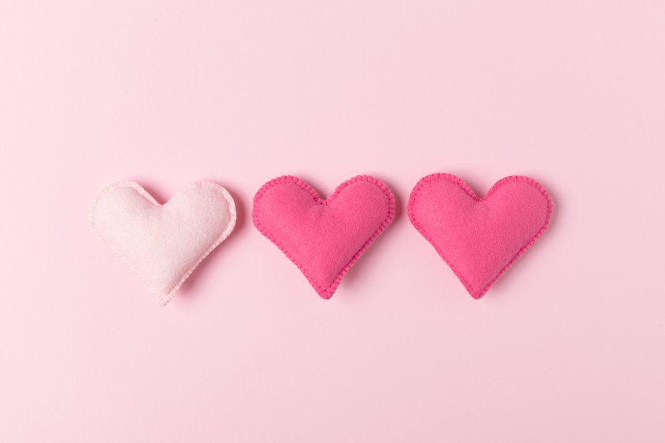 Fotografija: Three craft felt hearts on pastel pink background for love triangle, being third wheel or infidelity concept - hand made toys for relationships or threesome theme.