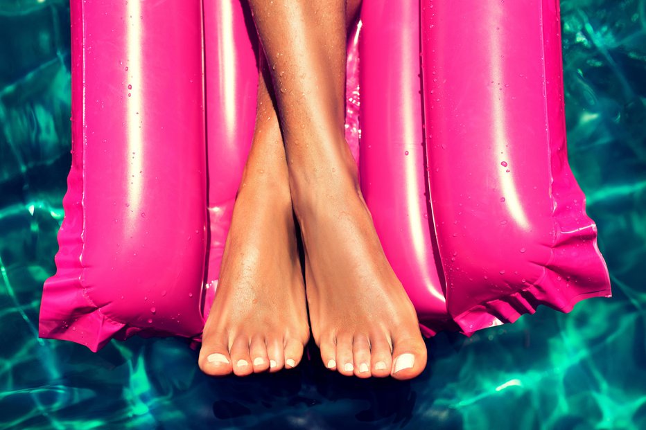 Fotografija: Tanned, well-groomed crossed woman's feet is laying in the pool on magenta inflatable mattress for swimming. Pedicure, feet care and Spa. Simbolik image of comfortable rest in vacation. FOTO: Thinkstock Getty Images/istockphoto