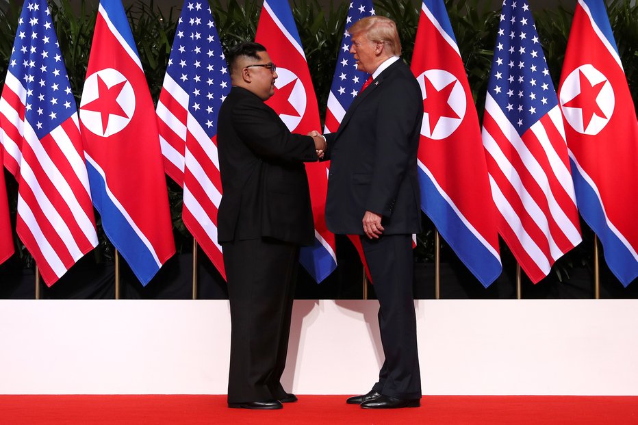 Fotografija: Donald Trump in Kim Džong Un sta si segla v roke. FOTO: Jonathan Ernst, Reuters