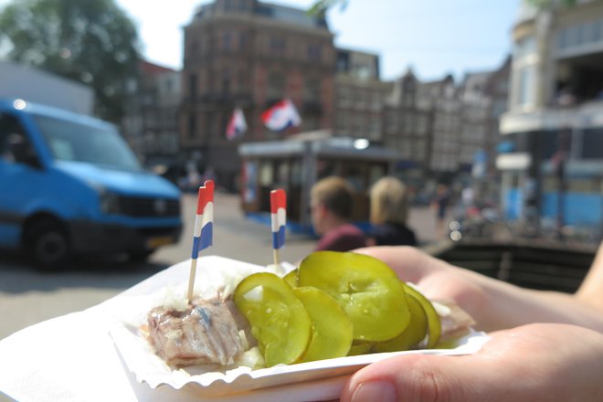 Riba, čebula in kumarice, v ozadju pa znana amsterdamska stojnica, kjer se poleg domačinov radi ustavijo tudi turisti.