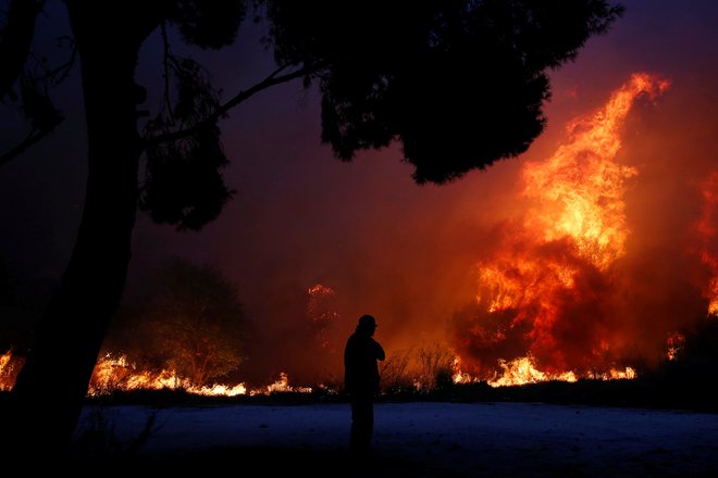 A man looks at the flames as a wildfire burns in the town of Rafina, near Athens, Greece, July 23, 2018. REUTERS/Costas Baltas      TPX IMAGES OF THE DAY