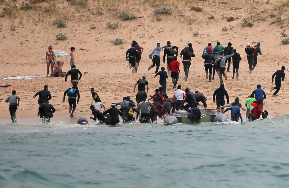 Fotografija: Migranti so se takoj po pristanku čolna razbežali na vse strani. FOTO: Reuters