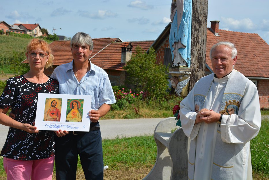Fotografija: V zahvalo za rešitev več kot 80 let starega križa je župnik Srečko Fras Stanislavu in Katici Filipič podaril sliko Jezusa in Marije. FOTO: OSTE BAKAL