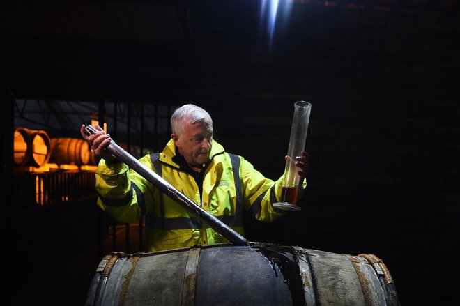 Uslužbenec destilarne Auchentoshan Nigel Baker med delom s sodi, v katerih viski starajo tudi do 25 let, preden ga pretočijo v steklenice. FOTO: AFP