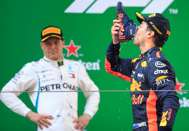Daniel Ricciardo (desno, ob njem Valtteri Bottas) je šanghajsko zmago proslavil v zanj značilnem slogu – s pitjem šampanjca iz svojega dirkalnega copata. FOTO: Reuters