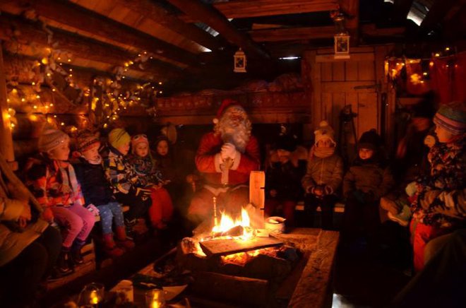 V toplo zakurjeni koči otroci prisluhnejo Božičkovim zgodbam.