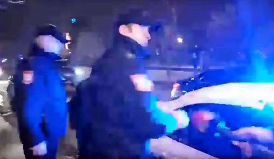 Fotografija: Policisti so domnevnega Slovenca posedli na zadnje sedeže policijskega vozila in ga odpeljali. FOTO: Youtube