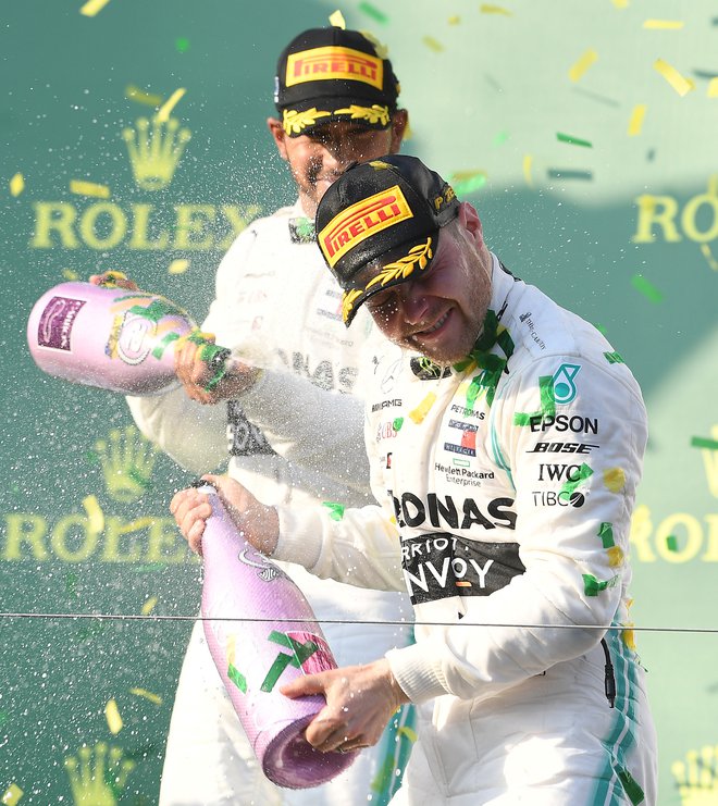 Lewis Hamilton (zadaj) je po včerajšnji dirki v Melbournu takole s šampanjcem poškropil zmagovalca Valtterija Bottasa. FOTO: Reuters