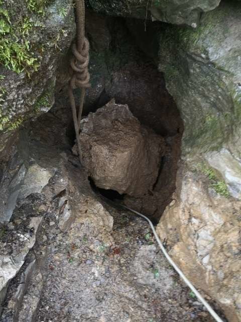 Fotografija: Med raziskovanjem je na vhod zaradi razmocenega terena padla skala, v jami pa sta ostala ujeta jamarja. FOTO: Igor Benko