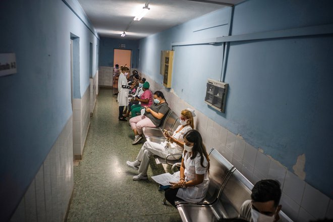 Takole čakajo na odmerek soberane 2 zdravstveni delavci, ki sodelujejo v testni raziskavi. Fotografiji: Ramon Espinosa/Reuters