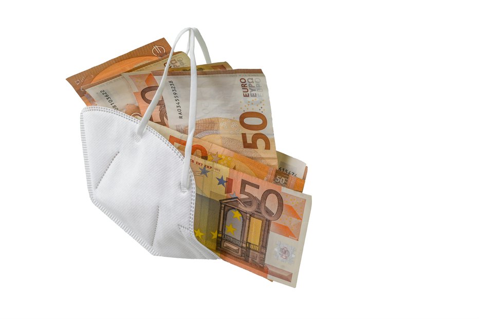 Fotografija: Medical ffp2 face mask against covid-19 virus filled with euro banknotes, concept for enrichment by corruption or rising costs of health care in pandemic crisis, isolated on a white background, copy space
