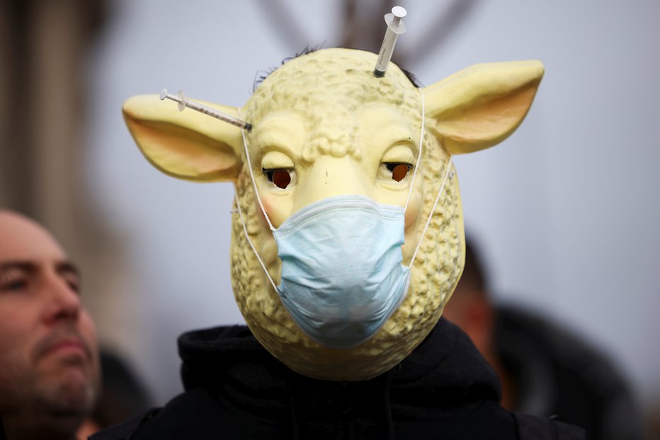 Fotografija: Oseba z masko na demonstracijah proti cepljenju na Parlamentarnem trgu v Londonu, Velika Britanija. FOTO: Henry Nicholls Reuters