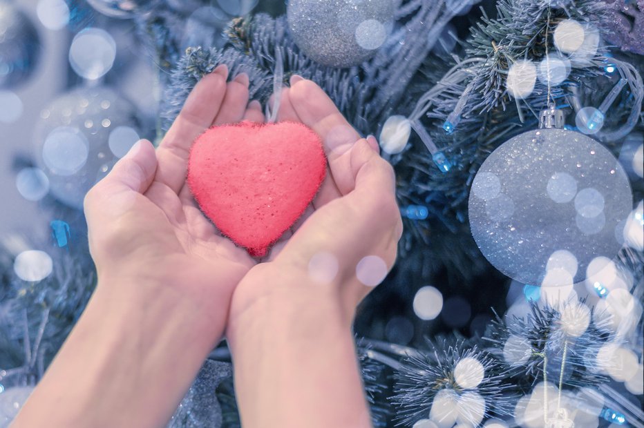 Fotografija: female hands hold heart on christmas tree. Blue christmas background