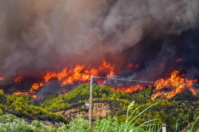 Požar na otoku Evia je viden z morja, gasilci pa imajo zaradi razgibanega terena težave z gašenjem. FOTO: Str/AFP