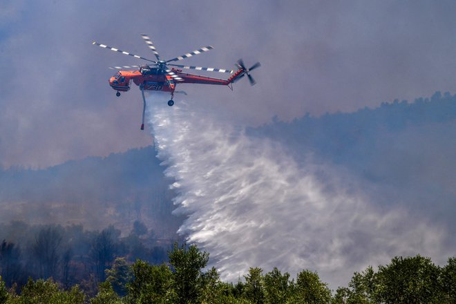 Helikopter Sikorsky S-64 gasi požar v vasi Platanos v bližini antične Olimpije. FOTO: Str/AFP