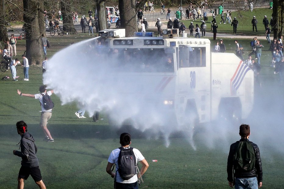 Fotografija: Mladi v Bruslju so se, siti omejevalnih ukrepov, množično zbrali v parku, posredovala je tudi policija z vodnim topom. Foto Francois Walschaerts/AFP