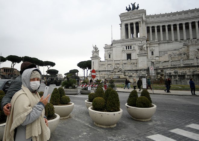 Turisti z maskami ob rimskem Vittorianu. Okužbe so potrdili v vseh italijanskih regijah z izjemo dveh na jugu države, Molizeja in Bazilikate. FOTO: Filippo Monteforte/AFP