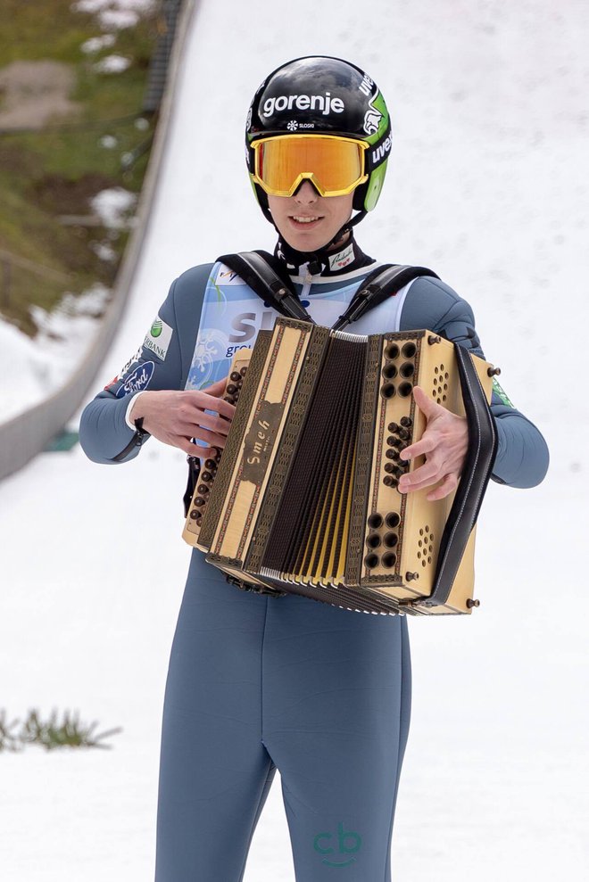 Timi Zajc je takole, s čelado na glavi, smučmi na nogah in harmoniko v roki, posnel videospot za skladbo Slovenskih zvokov Planiška polka.
