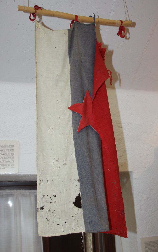 Na roke sešita slovenska zastava iz druge svetovne vojne
