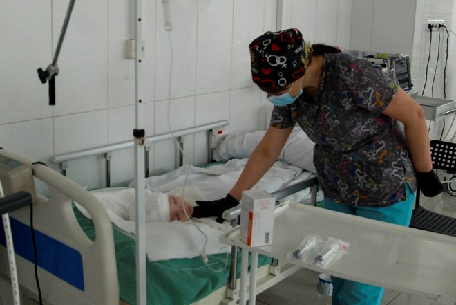 Medicinska sestra pri dečku, ki je bil ranjen med ruskim napadom na Harkov. FOTO: Stringer/Reuters

