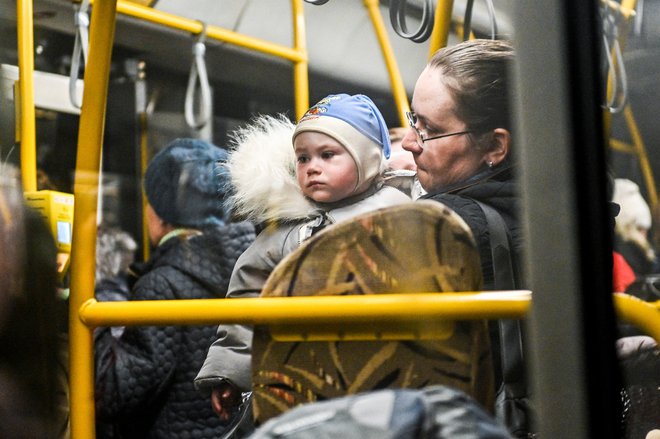 Ženska drži otroka v avtobusu za evakuacijo, ko ljudje bežijo iz Mariupolja in Melitopola med ruskim napadom na Ukrajino na zbirnem mestu v Zaporožju. FOTO: Stringer/Reuters
