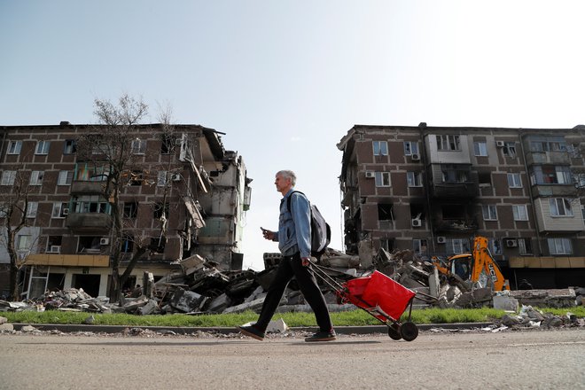 Prebivalec Mariupolja gre mimo uničenih zgradb. FOTO: Aleksander Ermočenko/Reuters
