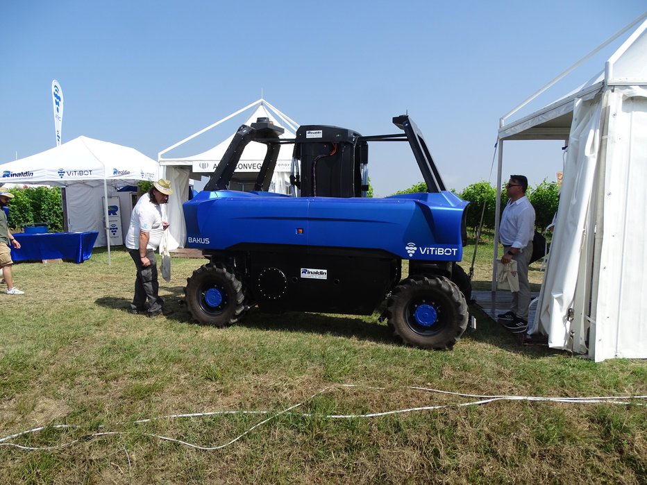 Fotografija: Bakus L je vinogradniški robot francoskega proizvajalca Vitibot. Je kolesne izvedbe s pnevmatikami michelin multibib 320/65R16 s tlakom 0,9 bara za manjše tlačenje tal. Kolesa se obračajo za 120 stopinj. Robot je jahalne izvedbe, se pravi, da nadjaha vrsto trte. Sredinska odprtina jahalnega traktorja za prehod trte je velika 2,2 x 0,8 m. Težek je 2100 kg. Je električne izvedbe s 60 kWh baterijo, moč pa naj bi bila 48 kW. Razvije hitrost do 6 km/h, dela pa lahko do 12 ur. Ima lahko pasivna ali električna orodja (delovne priključke). Za avtonomno vožnjo skrbijo dva sistema GPS RTK in 3D- kamere. FOTOGRAFIJE: Tomaž Poje
