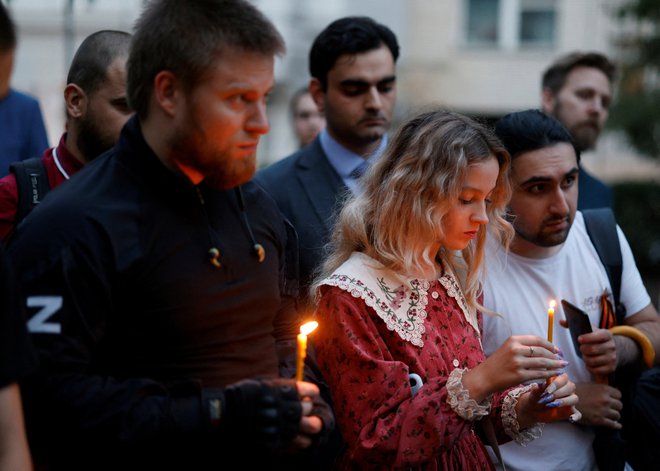 Ljudje držijo sveče ob improviziranem spomeniku medijski komentatorki.

 
