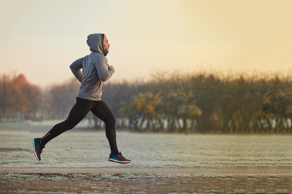 Fotografija: Young athletic man running at park during cold autumn morning
