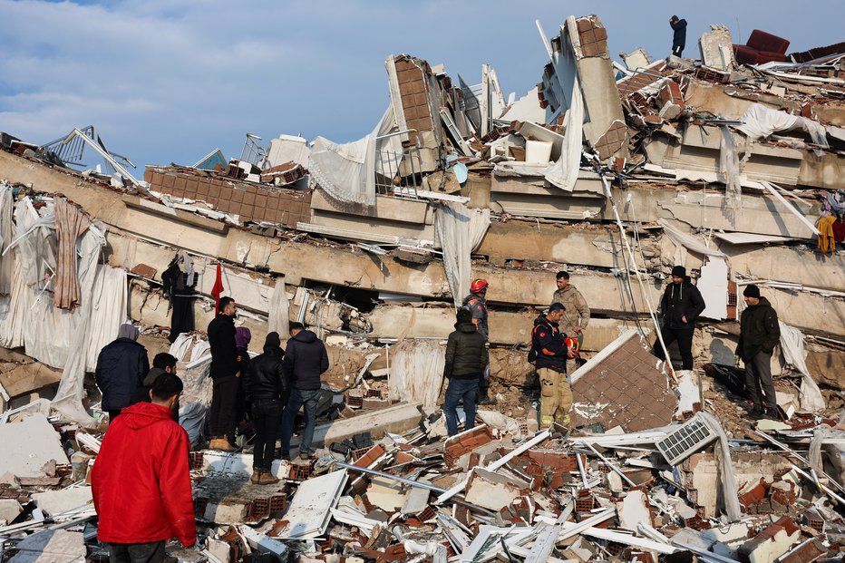 Fotografija: Ljudje opazujejo uničenje, medtem ko reševalci iščejo preživele v ruševinah po potresu v Hatayu v Turčiji, 7. februarja 2023. FOTO: Umit Bektas, Reuters
