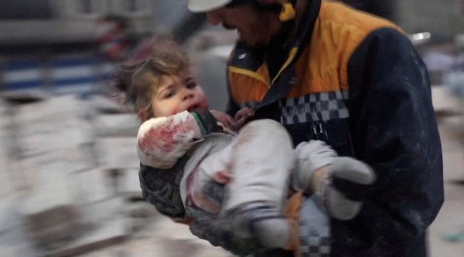 Reševalec nosi sirskega malčka Raghada Ismaila stran od ruševin stavbe po potresu v Azazu v Siriji, ki ga držijo uporniki. FOTO: Reuters Tv 
