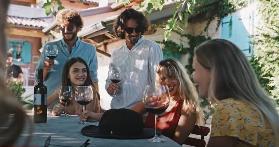 Fotografija: V enem izmed posnetkov novega promocijskega videa skupina prijateljev nazdravlja v čast 'lepi Italiji'. Ti prizori so bili posneti v vinski kleti v Sloveniji. FOTO: Zaslonski posnetek, youtube