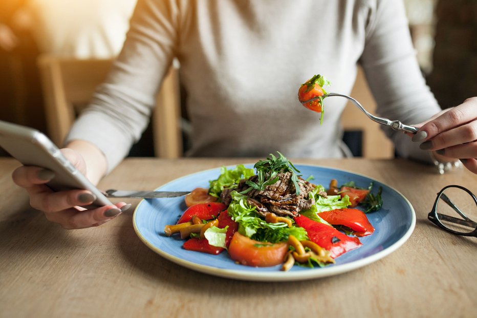 Fotografija: Brskanje po telefonu med obrokom. FOTO: Ahriv Polet/ Shutterstock 