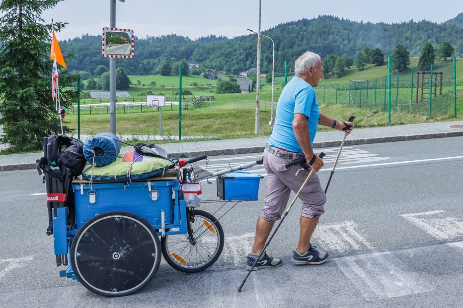 Fotografija: Za seboj vleče aluminijast voziček z vso opremo. FOTO: Miro Zalokar