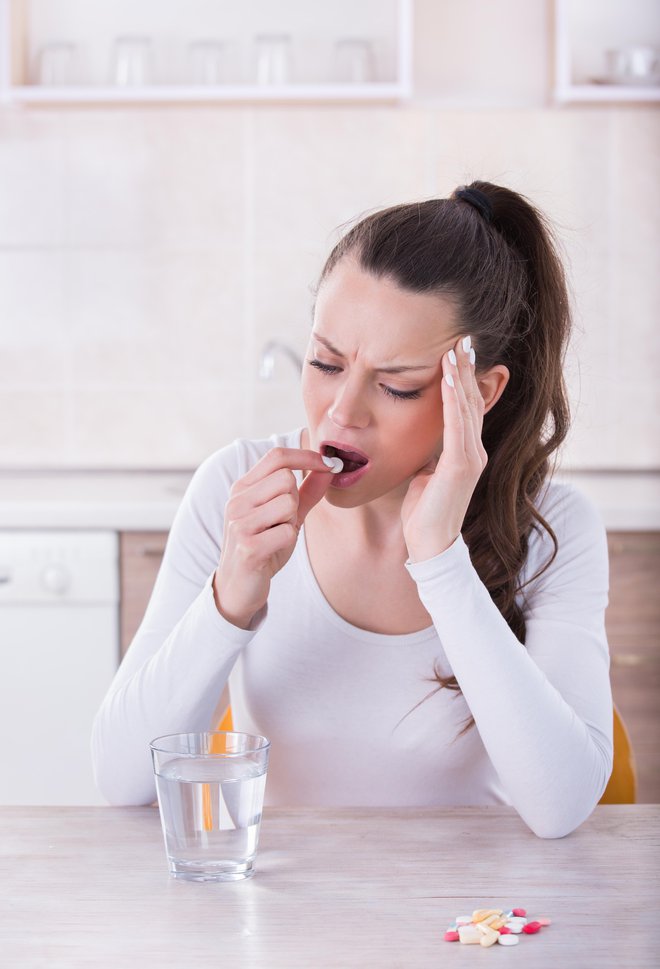 Young pretty woman having headache and taking pills at table in kitchen FOTO: Jevtic Getty Images/istockphoto