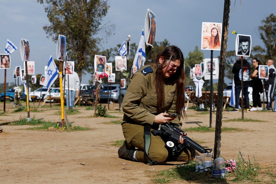 Fotografija: Izraelska vojakinja ob spomeniku umrlim članom njene družine. FOTO: Tyrone Siu, Reuters