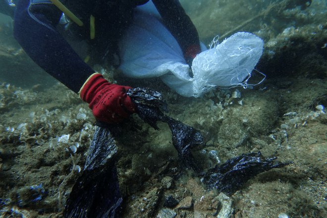 Potapljač okoljevarstvene organizacije Aegean Rebreath pobira plastične odpadke z morskega dna v bližini otoka Andros. FOTO: Stelios Misinas/Reuters