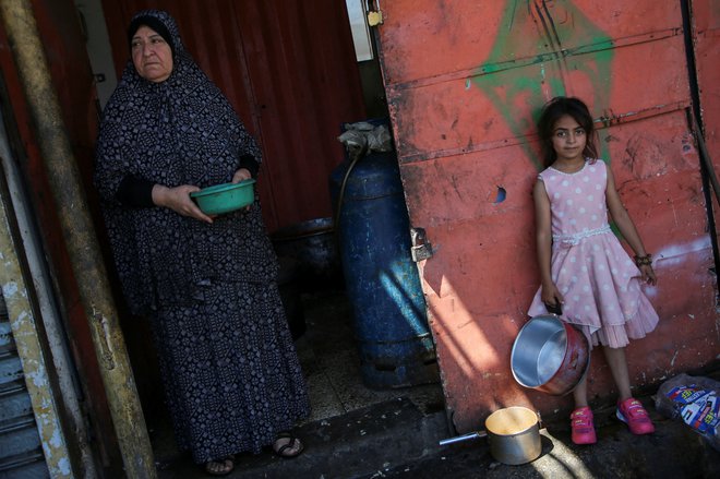Palestinki čakata na hrano, skuhano v dobrodelni kuhinji, medtem ko Izrael napada vzhod Rafe. FOTO: Hatem Khaled Reuters
